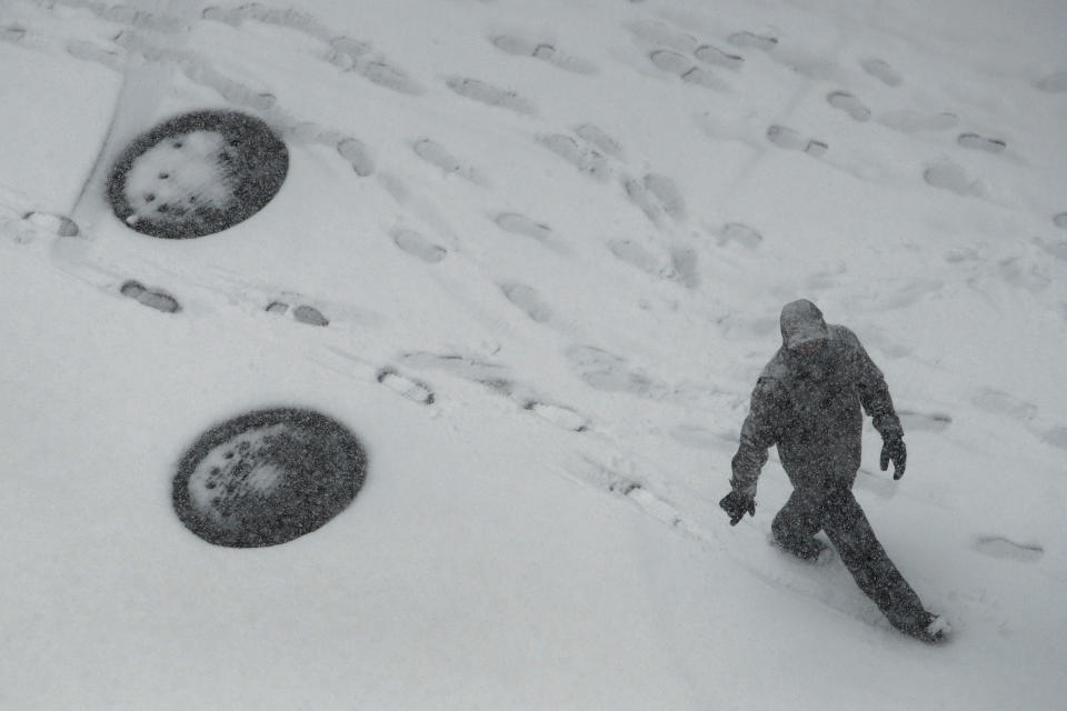 A pedestrian walks as snow falls Sunday, Nov. 25, 2018, in downtown Kansas City, Mo. Blizzard-like conditions have closed highways and delayed air travel as a winter storm moves through the midwest. (AP Photo/Charlie Riedel)