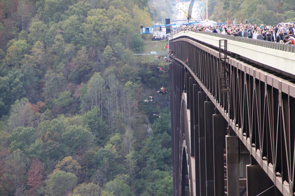 Spectators peer over the edge of New River Gorge Bridge as BASE jumpers take the leap on Bridge Day.