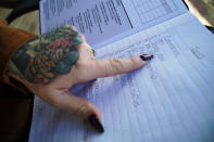 Melissa Sell points to entries in what her husband calls her “conspiracy journal” on the front porch of their home in Mount Holly Springs, Pa., on Tuesday, Oct. 31, 2023. When something piques her interest, the 34-year-old mother of one jots it down for further research. Sell said she began to lose trust in the government and the media shortly after the 2012 Sandy Hook school shooting in Newtown, Conn., which left 20 students and six teachers dead. Sell thought the shooter looked too small and weak to carry out such a bloody act. And the gut-wrenching interviews with stricken loved ones seemed too perfect, almost practiced. (AP Photo/Allen G. Breed)