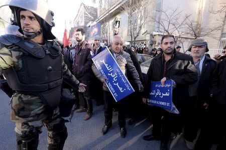 An Iranian riot police stands guard as protesters hold street signs with the name of Shi'ite cleric Sheikh Nimr al-Nimr during a demonstration against the execution of Nimr in Saudi Arabia, outside the Saudi Arabian Embassy in Tehran January, 3, 2016. REUTERS/Raheb Homavandi/TIMA