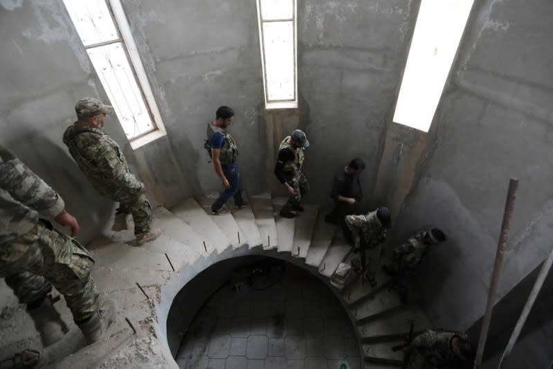 Turkey-backed Syrian rebel fighters walk inside a building they use to shelter near the border town of Tal Abyad