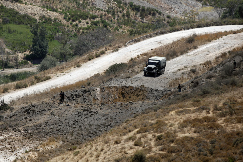 Lebanese troops stand next to a crater caused by an Israeli airstrike in Dimashqiya farmlands, southern Lebanon, Thursday, Aug 5, 2021. Israel on Thursday escalated its response to rocket attacks this week by launching rare airstrikes on Lebanon, the army and Lebanese officials said. (AP Photo/Mohammed Zaatari)