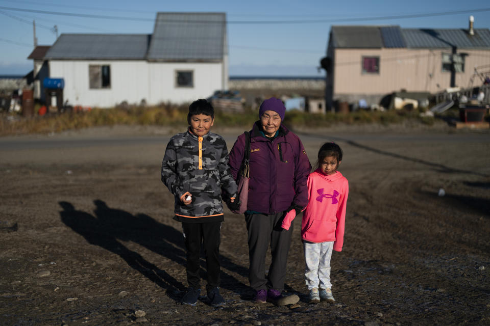 Ardith Weyiouanna, center, holds the hand of her grandchildren, Isaac Olanna, left, and Kyle Rose Olanna as they stand for a photo after attending a Sunday service at the Shishmaref Lutheran Church in Shishmaref, Alaska, Sunday, Oct. 2, 2022. "To move somewhere else, we'd lose a part of our identity. It's hard to see myself living elsewhere," said Weyiouanna, whose family first came to Shishmaref with a dogsled team in 1958. (AP Photo/Jae C. Hong)