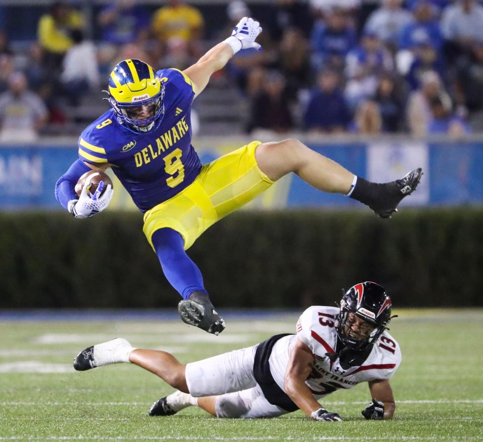 Delaware tight end Braden Brose is tripped up after a reception by Saint Francis defensive back Buju Aumua-Tuisavura in the third quarter of the Blue Hens' 42-14 win at Delaware Stadium, Saturday Sept. 16, 2023.