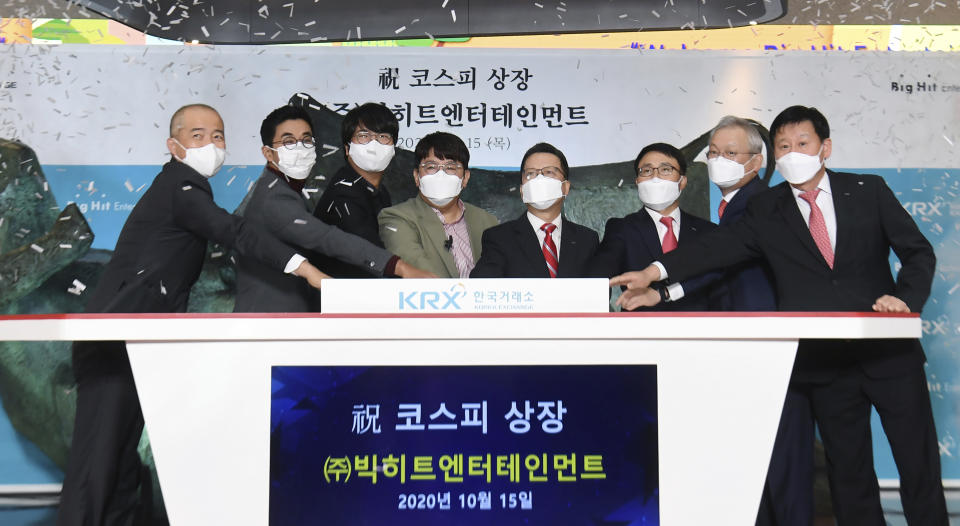 Big Hit Entertainment Ltd.’s Chairman and CEO Bang Si-Hyuk, fourth from left, poses with other participants for the media during the listing ceremony of the compnay at the Korea Exchange in Seoul, South Korea, Thursday, Oct. 15, 2020. The company, that manages boy band BTS made its market debut amid criticism by Chinese internet users after the group’s leader thanked Korean War veterans for their sacrifices. (Korea Pool/Yonhap via AP)