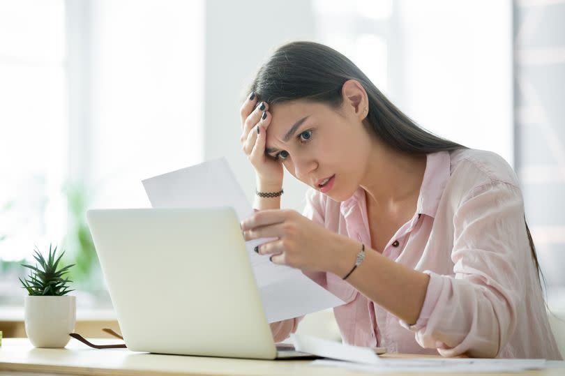 A woman looking frustrated as she reads a rejection letter