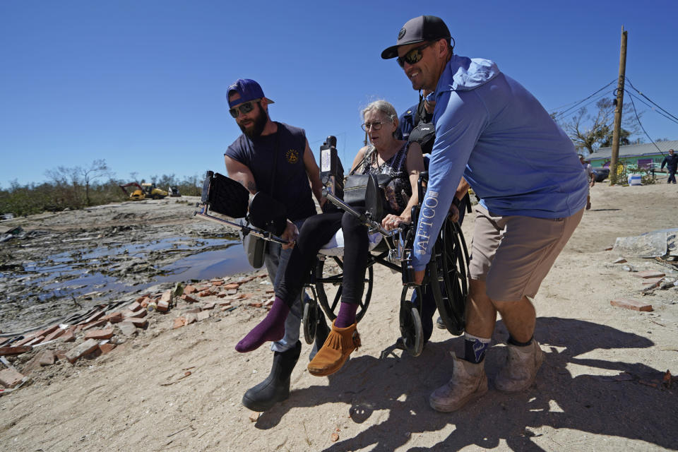 FILE - Rescuers help evacuate Suzanne Tomlinson, a resident who rode out the storm, as they carry her to a waiting boat in the aftermath of Hurricane Ian on Florida's Pine Island in Lee County, Sunday, Oct. 2, 2022. The only bridge to the island was heavily damaged so it can only be reached by boat or air. Older people with limited mobility and chronic health conditions were especially vulnerable when Hurricane Ian slammed into Southwest Florida last month. (AP Photo/Gerald Herbert, File)