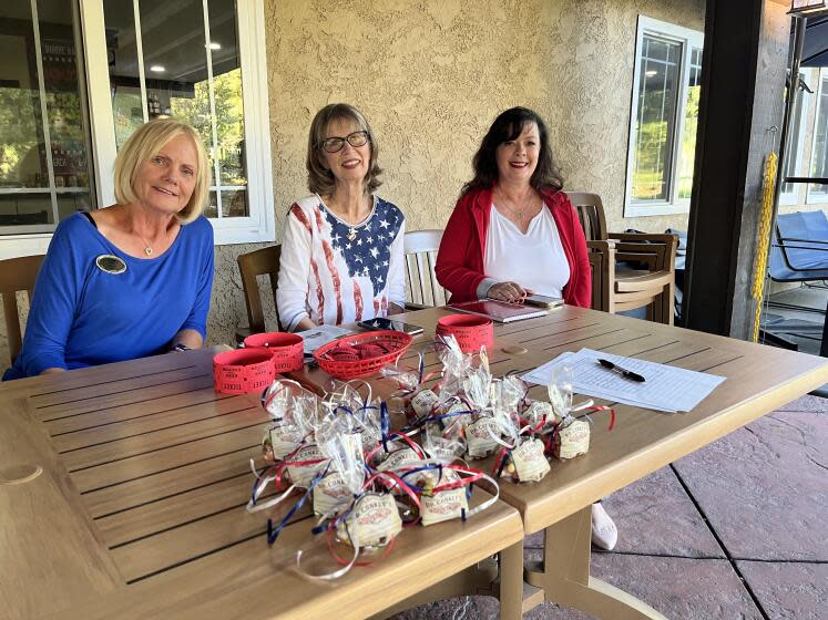 Three women in red, white and blue sit behind a table with baggies of jelly beans.