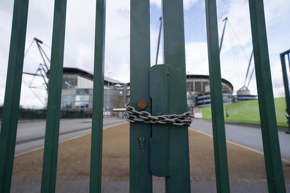 A locked gate is seen by the Etihad Stadium where Manchester City was due to play Burnley in an English Premier League soccer match Saturday March 14, 2020, after all English soccer games were cancelled due to the spread of the COVID-19 Coronavirus. For most people, the new COVID-19 coronavirus causes only mild or moderate symptoms, but for some it can cause more severe illness. (AP Photo/Jon Super)