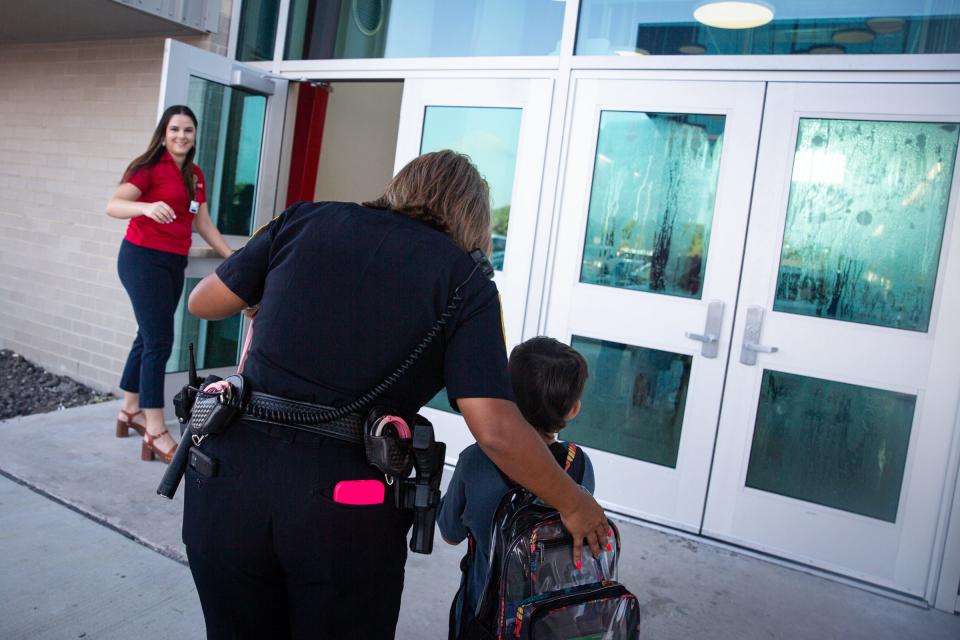 A student is helped into school by an officer on the first day of school at Cullen Place Elementary, Wednesday, Aug. 9, 2023, in Corpus Christi, Texas.