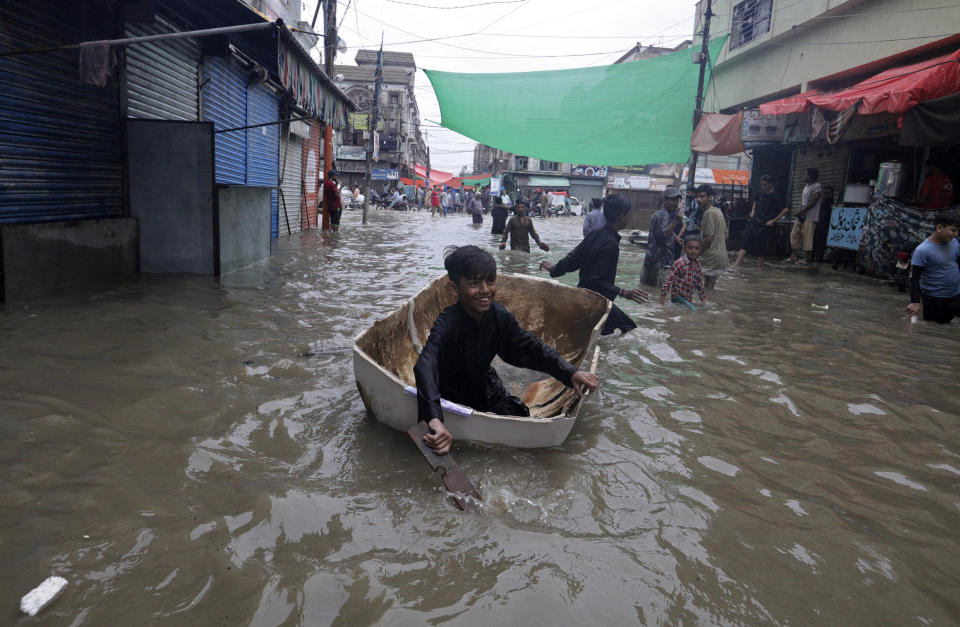 A boy uses half of a fiber tank to navigate a flooded street after heavy monsoon rains, in Karachi, Pakistan, Thursday, Aug. 27, 2020. Heavy monsoon rains have lashed many parts of Pakistan as well the southern port city of Karachi, leaving flooding streets, damaging homes and displacing scores of people. (AP Photo/Fareed Khan)
