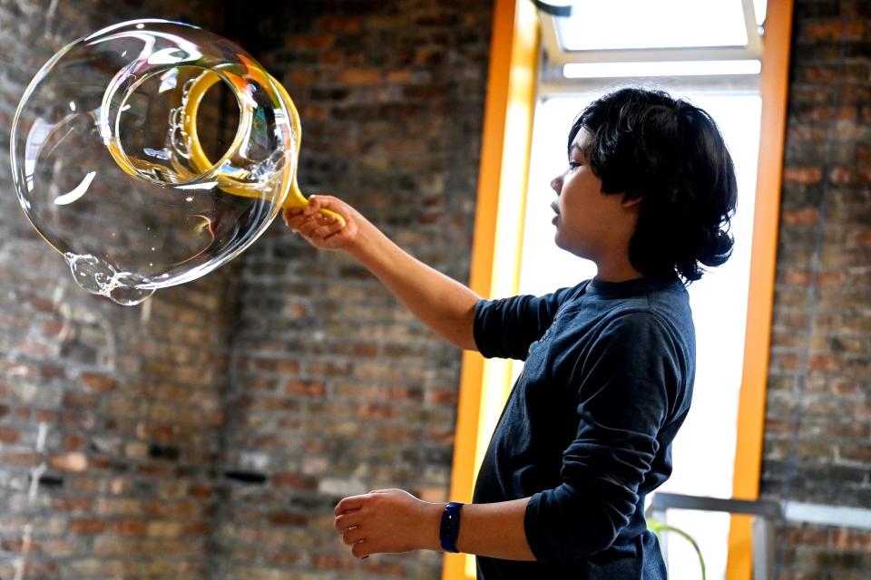 Santiago Henning, 13, makes a large bubble inside the Pop! A Bubble Experience exhibit on Saturday, Dec. 3, 2022, at the Impression 5 Science Center in Lansing.