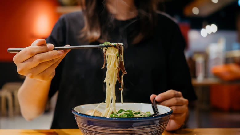 lifting noodles out of bowl with chopsticks 