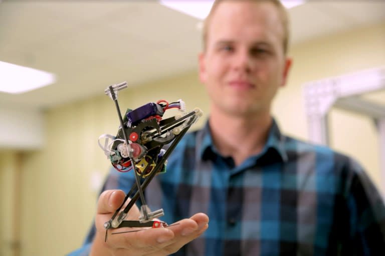 Researcher Duncan Haldane holds a robot known as Salto