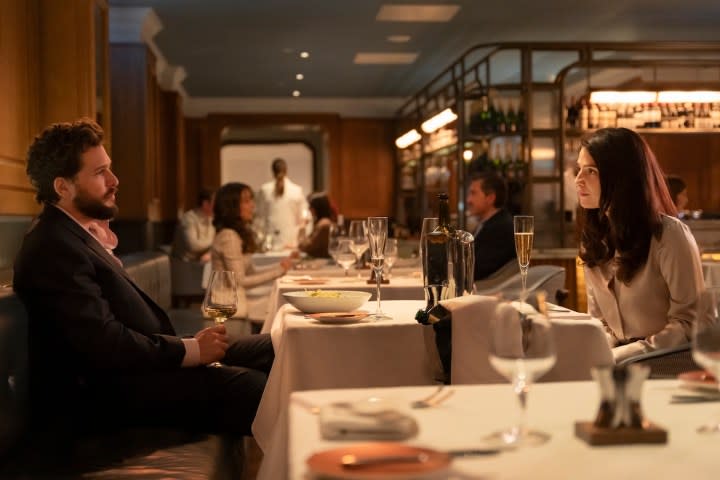 A man and woman sit across from each other at a table.