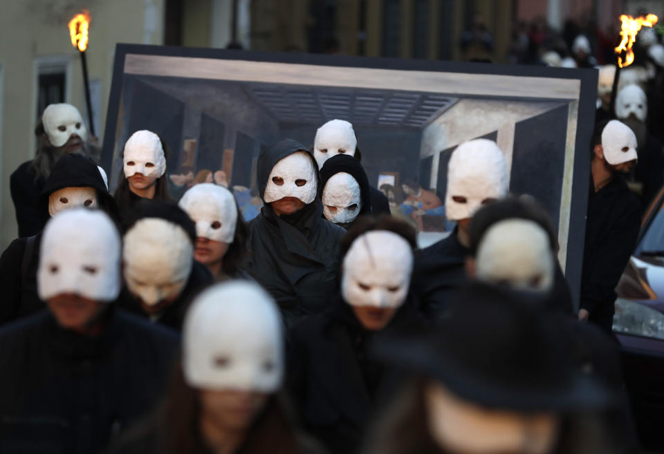 In this picture taken on Thursday, April 18, 2019, participants dressed in black, wearing masks, beating drums and pushing small carts that make a synchronized and loud sound take part in an Easter procession through the streets of Ceske Budejovice, Czech Republic. (AP Photo/Petr David Josek)