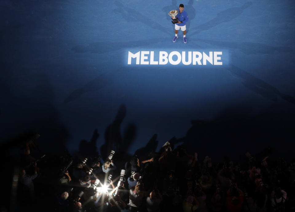 In this Sunday, Jan. 27, 2019, file photo, Serbia's Novak Djokovic, top, poses for photograhers, at bottom, with his trophy after defeating Spain's Rafael Nadal in the men's singles final at the Australian Open tennis championships in Melbourne, Australia. (AP Photo/Mark Schiefelbein, File)