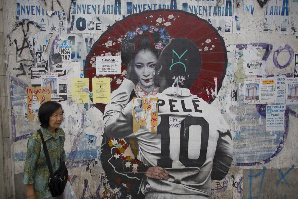 In this Dec. 27, 2018 photo, a woman walks by a mural of Brazilian soccer legend Pele hugging a Geisha in Sao Paulo, Brazil's Asian neighborhood of Liberdade, the area where an influential Japanese-language newspaper ran its last print edition on Jan. 1, 2019. The arrival of the first Japanese immigrants to Brazil was the result of negotiations between Japan and Sao Paulo state, where most Japanese-Brazilians still live. (AP Photo/Victor R. Caivano)