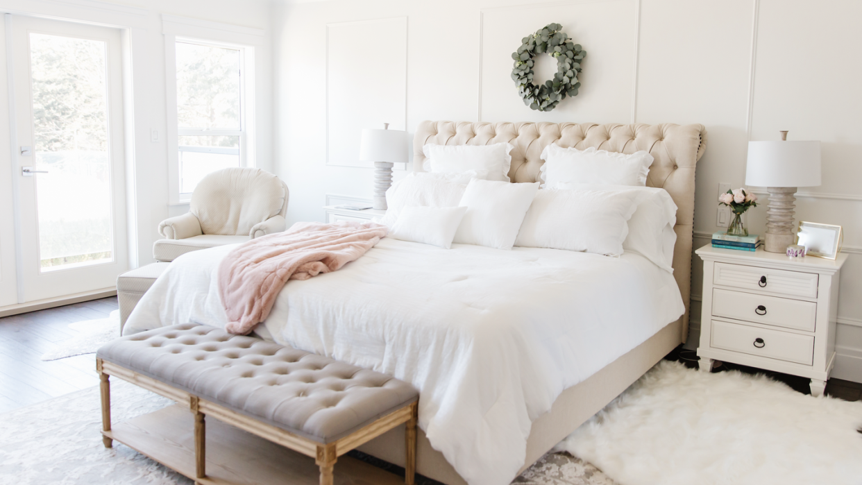 master bedroom with big windows and a large comfy bed in the middle of the room with fluffy white cover and pillows on the bed