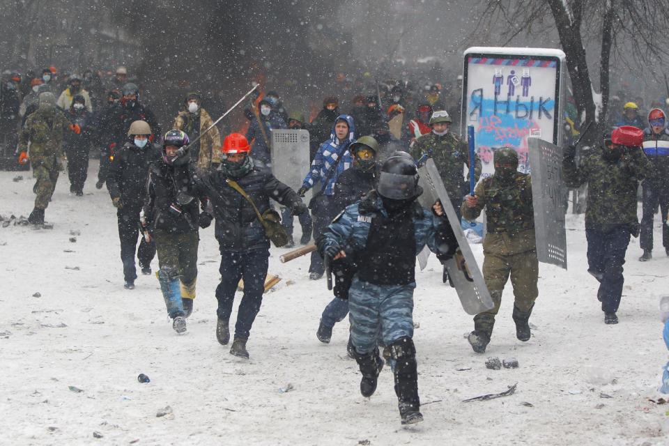 A police officer runs away during clashes with protesters in central Kiev, Ukraine, Wednesday, Jan. 22, 2014. Two protesters whose bodies were found Wednesday near the site of clashes with police were shot with live ammunition, prosecutors said Wednesday, raising fears that their deaths — the first after two months of largely peaceful protests — could further fuel violence on the streets of the Ukrainian capital. (AP Photo/Sergei Grits)