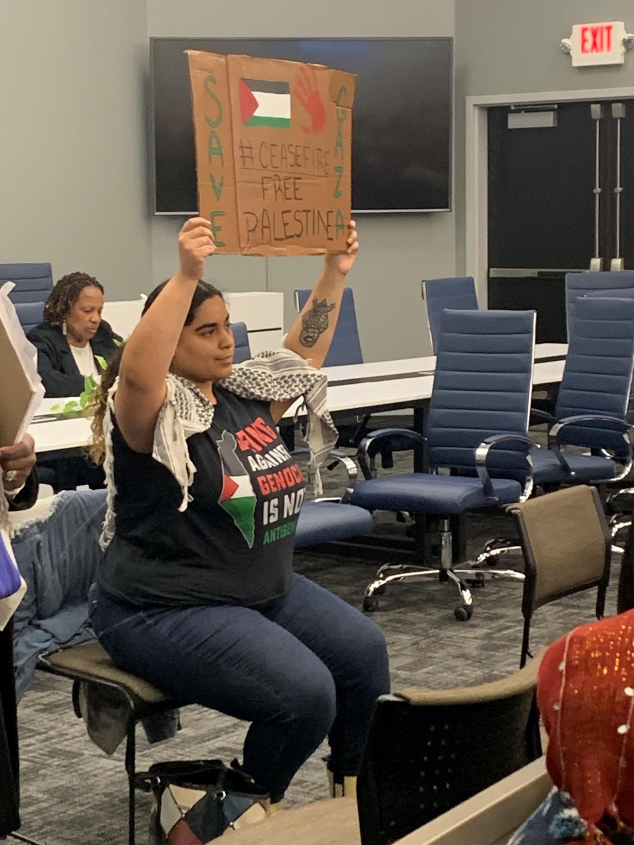 Isabel Juarez of Canton Township holds a sign calling for a cease-fire resolution in the Israel-Hamas war during Monday's Canton City Council meeting. An increasing number of Stark County residents have been attending the Canton Council meetings since mid-February to ask council to adopt a cease-fire resolution.