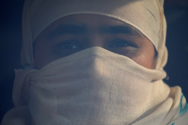 A woman covers her face using a shawl as she sits inside a long distance bus to leave for her village, amid concerns about the spread of the coronavirus disease (COVID-19) outbreak, in Kathmandu