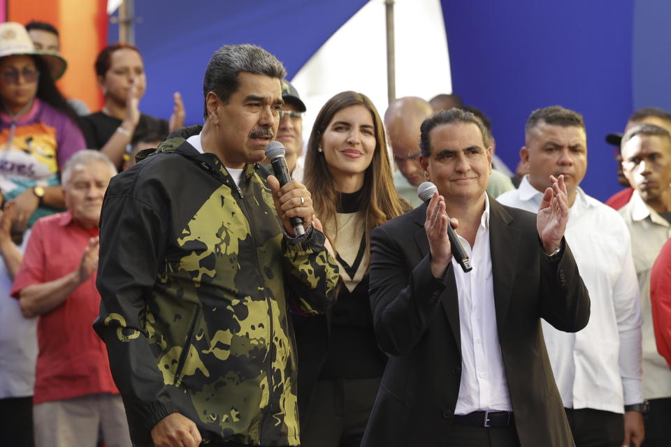 Venezuela's President Nicolas Maduro speaks as Alex Saab applauds, accompanied by his wife Camilla Fabri, during an event marking the anniversary of the 1958 coup that overthrew dictator Marcos Perez Jimenez, in Caracas, Venezuela, Tuesday, Jan. 23, 2024. (AP Photo/Jesus Vargas)