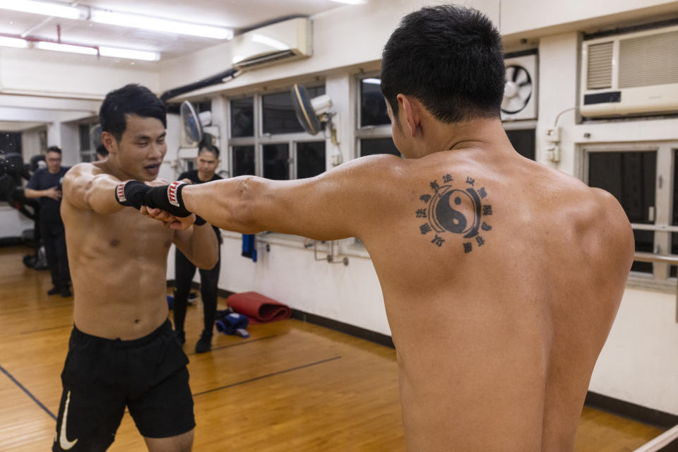 Adrian Li trains as he wears a tattoo representing the Jeet Kune Do Emblem which traditional Chinese characters read: "Using no way as way" and "Having no limitation as limitation" during a Jeet Kune Do class in Hong Kong, Wednesday, July 19, 2023. (AP Photo/Louise Delmotte)