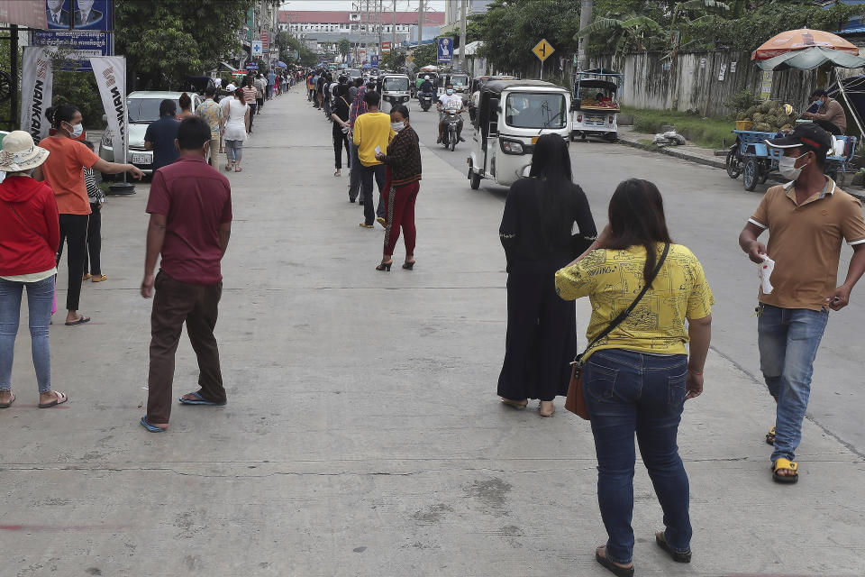 Villagers line up on a street as they wait to get their first dose of the Sinovac COVID-19 vaccine at an injection center near Tuol Sangke main market, in Phnom Penh, Cambodia, Monday, May 24, 2021. (AP Photo/Heng Sinith)