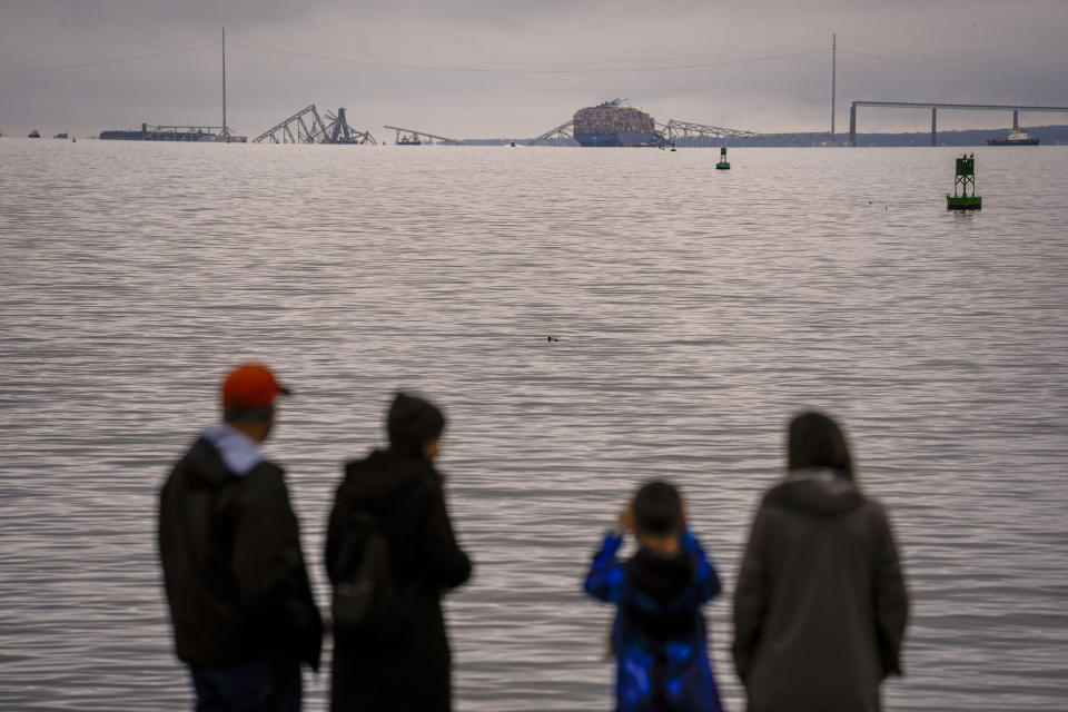 People at Fort Mchenry view a container ship as it rests against the wreckage of the Francis Scott Key Bridge on Wednesday, March 27, 2024, in Baltimore. The ship rammed into the major bridge early Tuesday, causing it to collapse in a matter of seconds and creating a terrifying scene as several vehicles plunged into the chilly river below. (AP Photo/Matt Rourke)