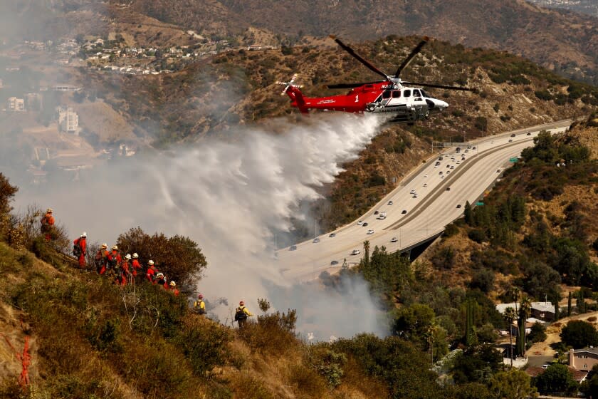 Al Seib  Los Angeles Times Crews fight blaze by land and air A helicopter makes a water drop as an inmate hand crew extinguishes hot spots Monday morning on a 30-acre brush fire that started Sunday in Eagle Rock. About 100 homes in Glendale were evacuated.