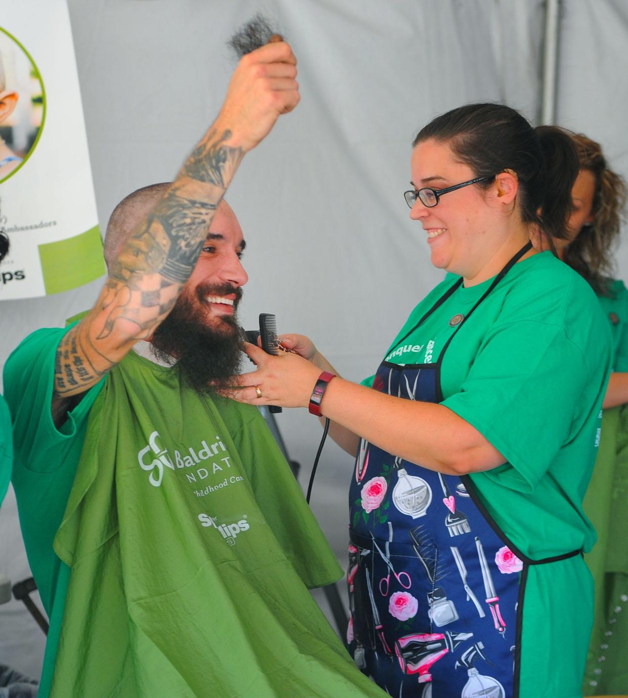 Charlie Miller holds up hair from his beard, which had been growing for two years as stylist Amy Miller proceeds to remove the remainder of it Sunday, Sept. 18, 2022, during the 7th annual Alliance St. Baldricks fundraiser. Miller raised more than $1,100 in donations for cancer research.