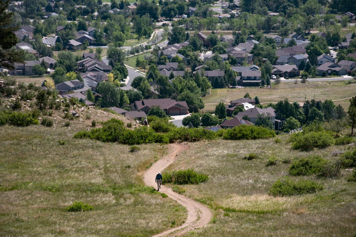 A hiker walks up along the Foothills Trail with an overview of homes in Fort Collins on Wednesday, June 15, 2022.