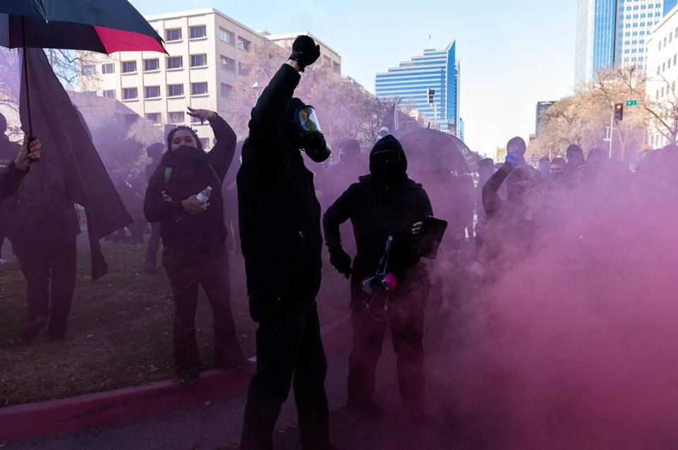 Black-clad protesters light smoke bombs at Capital Mall and 9th Street on Inauguration Day, Wednesday, Jan. 20, 2021 at the State Capitol in Sacramento.