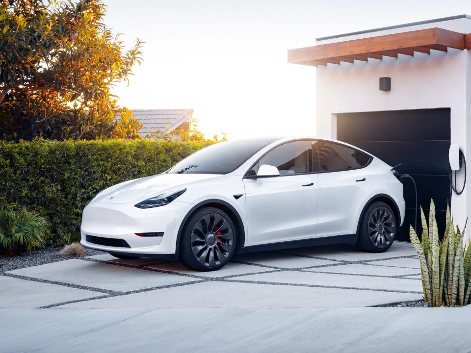 The Tesla Model Y electric SUV charging at a home.