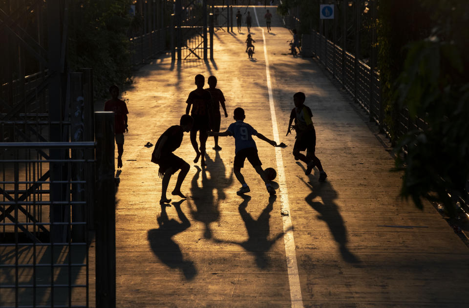 Children play soccer in the afternoon light in Bangkok, Thailand, Wednesday, March 25, 2020. Thailand's government announced a state of emergency to start on Thursday, March 26, 2020, to allow measures that might be needed to control the coronavirus outbreak that has infected hundreds of people in the Southeast Asian country. (AP Photo/Gemunu Amarasinghe)