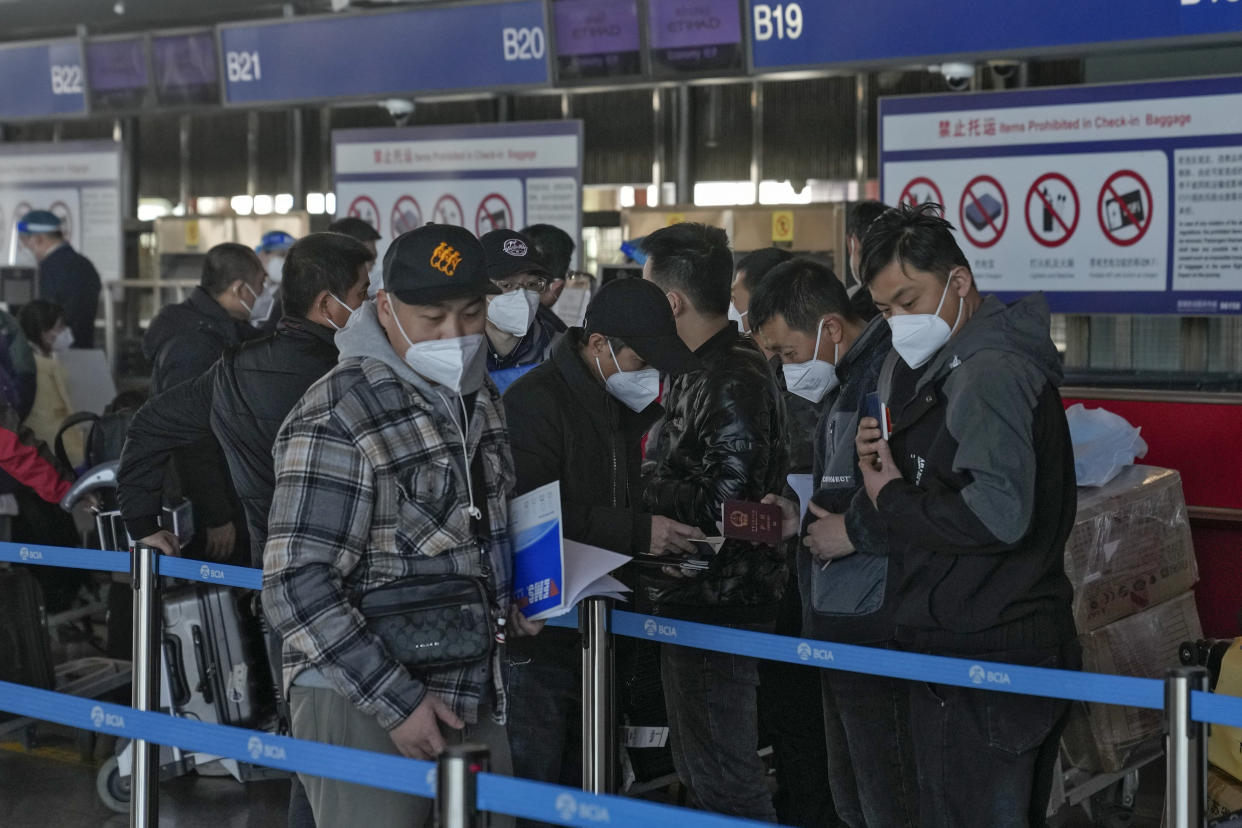 Masked travellers check their passports as they line up at the international flight check in counter at the Beijing Capital International Airport in Beijing, Thursday, Dec. 29, 2022. Moves by the U.S., Japan and others to mandate COVID-19 tests for passengers arriving from China reflect global concern that new variants could emerge in its ongoing explosive outbreak — and the government may not inform the rest of the world quickly enough. (AP Photo/Andy Wong)