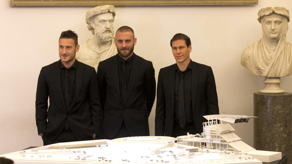 From left, Roma's Francesco Totti, Daniele De Rossi and coach Rudi Garcia pose on the occasion of the presentation of the new Roma soccer stadium, at Rome's Capitol Hill, Wednesday March 26, 2014. Three-time Serie A champion Roma has revealed plans to build a new privately financed stadium on the outskirts of the Italian capital. Labeled "Stadio della Roma" for now, until naming rights are awarded, the facility will seat 52,500 spectators and be expandable to 60,000 for major matches. Building costs for the stadium itself are estimated at 300 million euros ($414 million) but the overall price, including surrounding infrastructure and transport, will run far higher. The new stadium will be in the Tor di Valle area in the city's southwest, about halfway between downtown and Fiumicino airport. (AP Photo/Alessandra Tarantino)