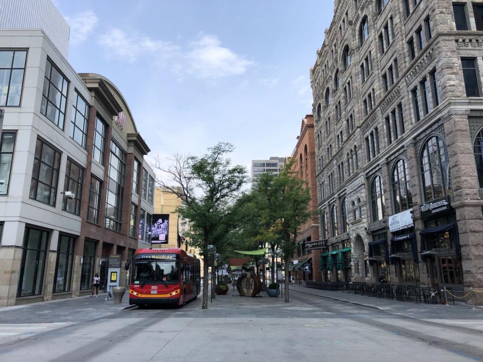 A public bus in a bus-only lane, flanked by pedestrian areas.