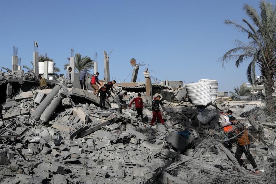 Palestinians walk among rubble of buildings in Al-Nuseirat refugee camp in Gaza on 22 December after it was bombed by Israeli airstrikes. (EPA)