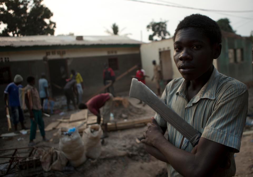 A young neighborhood resident carries a machete as other residents, returning from a makeshift camp for the displaced at Mpoko Airport, loot a damaged house in the Garaba neighborhood, in Bangui, Central African Republic, on New Year's Day, Wednesday, Jan. 1, 2014. Clashes between armed gangs of Muslim and Christian residents continued in the 5th Arrondissement area on Wednesday, with neighborhood residents reporting at least four people killed. In Garaba, several homes belonging to Christians were burned, and multiple Muslim homes looted. (AP Photo/Rebecca Blackwell)