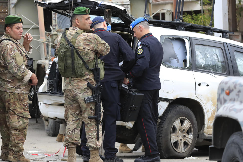 UN peacekeepers military police, right, investigate a damaged UN peacekeeper vehicle at the scene where a UN peacekeeper convoy came under gunfire in the Al-Aqbiya village, south Lebanon, Thursday, Dec. 15, 2022. (AP Photo/Mohammed Zaatari)