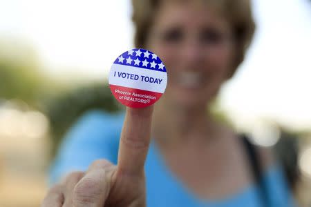 Deborah Kelly, who waited in line 45 minutes to vote in a U.S. presidential primary election, shows her voting sticker outside a polling site in Glendale, Arizona March 22, 2016. REUTERS/Nancy Wiechec