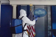 FILE - In this Oct. 5, 2020, file photo, a member of the cleaning staff sprays The James Brady Briefing Room of the White House, Monday, Oct. 5, 2020, in Washington. The U.S. death toll from the coronavirus has eclipsed 400,000 in the waning hours in office for President Donald Trump. (AP Photo/Alex Brandon, File)