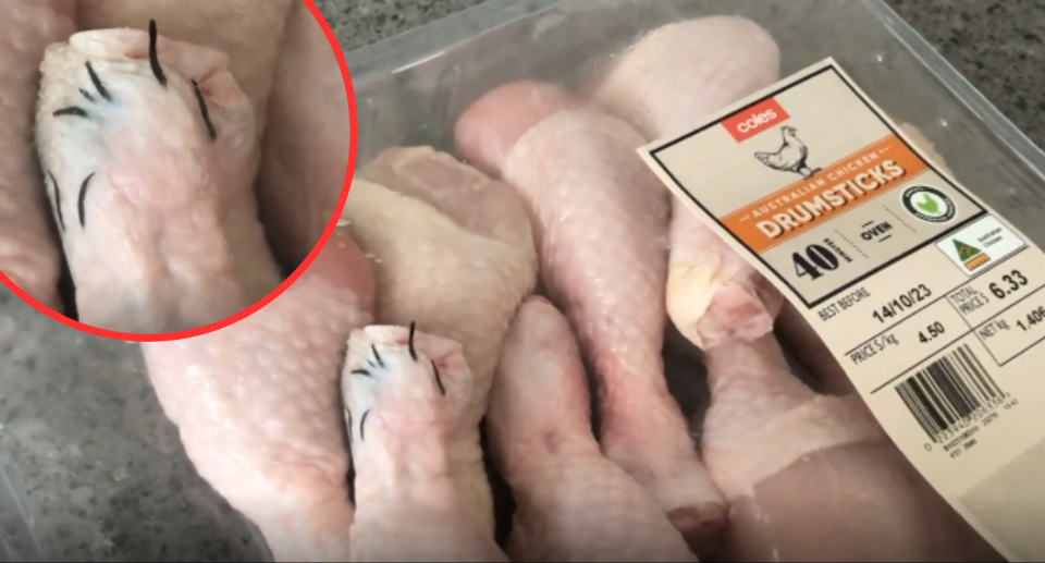 Photo of raw chicken drumsticks in clear Coles packaging. One leg has black needle looking things poking out of it.