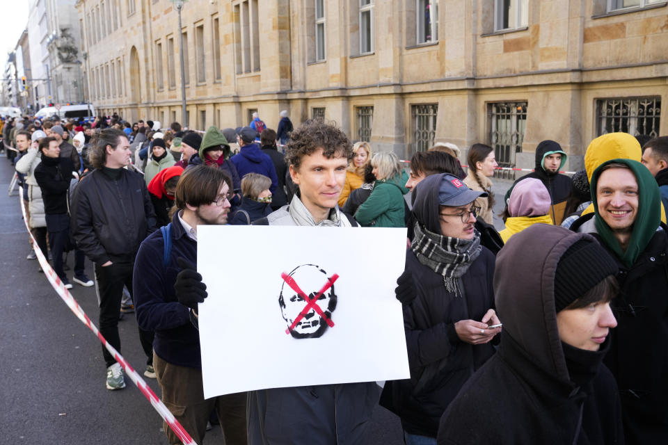 A man shows a protest placard as he queues with other voters near the polling station at the Russian embassy in Berlin, at noon local time on Sunday, March 17, 2024. The Russian opposition has called on people to head to polling stations at noon on Sunday in protest as voting takes place on the last day of a presidential election that is all but certain to extend President Vladimir Putin's rule after he clamped down on dissent. AP can't confirm that all the voters seen at the polling station at noon were taking part in the opposition protest.(AP Photo/Ebrahim Noroozi)