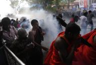 Students run for cover as police fire tear gas to disperse protesting members of the Inter University Students Federation during an anti government protest in Colombo, Sri Lanka, Thursday, May 19, 2022. Sri Lankans have been protesting for more than a month demanding the resignation of President Gotabaya Rajapaksa, holding him responsible for the country's worst economic crisis in recent memory. (AP Photo/Eranga Jayawardena)