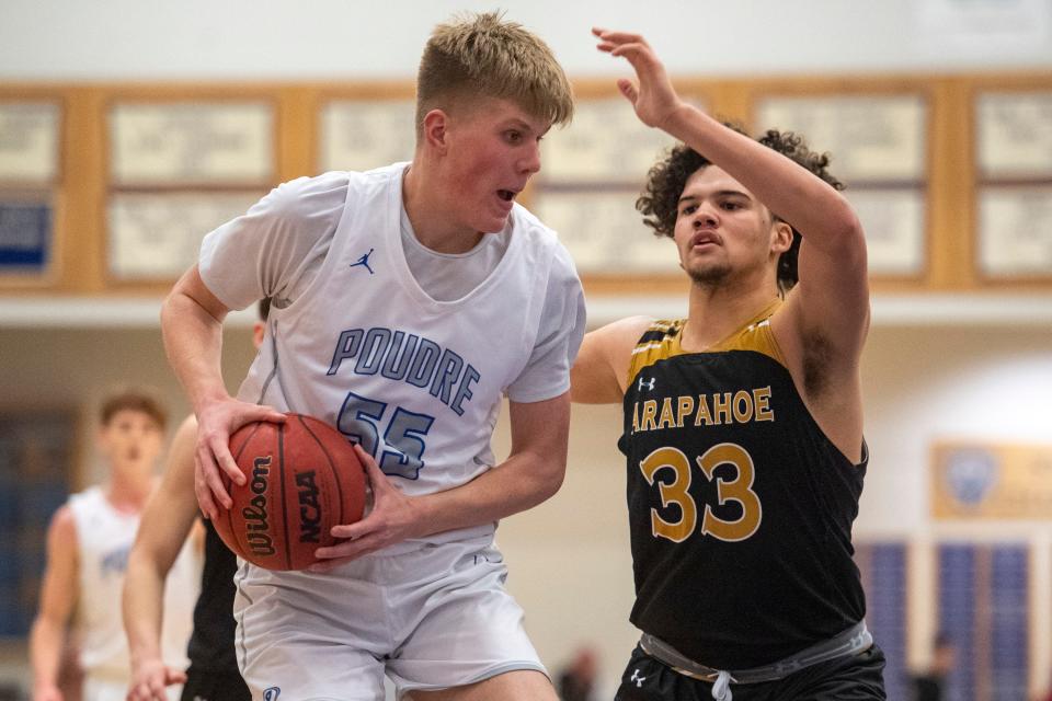 Poudre's Kaden Cox maneuvers under the basket while defended by Arapahoe's Cass Henry during the teams' 5A playoff game on Feb. 23, 2022, at Poudre High School.