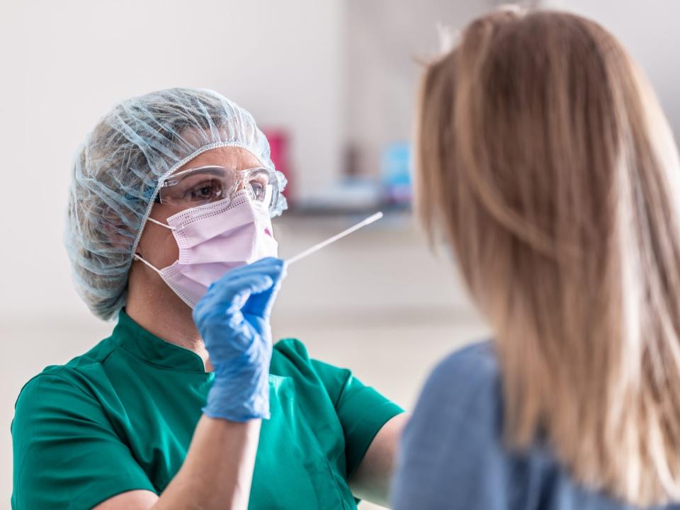 A nurse provides a COVID test to a female patient.