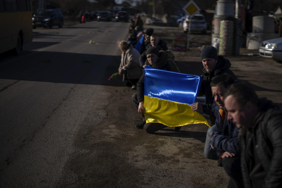 People kneel as the coffin containing the body of Serhii, 48, passes by during his funeral procession in Tarasivka village, near Kyiv, Ukraine, Wednesday, Feb. 15, 2023. Serhii Havryliuk, an officer of the Azov Assault Brigade, died while defending the Azovstal steel plant in Mariupol on April 12, 2022 against the Russians. Serhii has finally been buried after DNA tests confirmed his identity. (AP Photo/Emilio Morenatti)